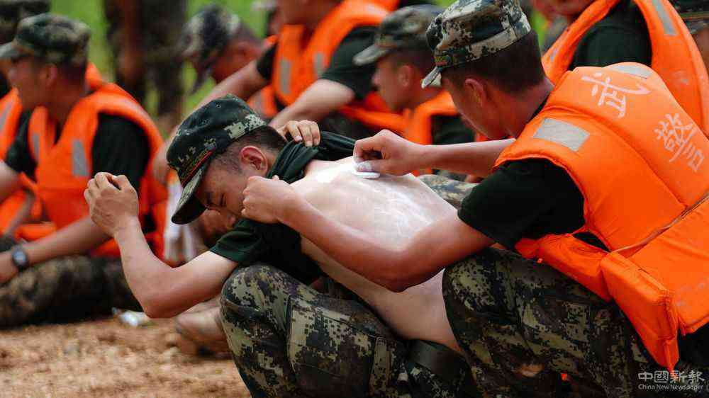 7月11日，在江西省鄱阳县江家岭村，武警战士在执行抗洪任务的休息间隙互相涂抹药粉，连日奋战让许多战士长痱子或晒伤。新华社记者 周密 摄