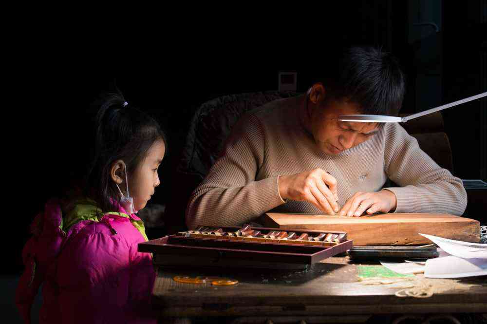 1月7日，在陕西西安明清皮影艺术博物馆，一名前来参观的小女孩被王可现场制作皮影吸引，驻足观看。